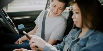 asian chinese young couple checking on phone GPS at road side before the road trip in the morning