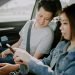 asian chinese young couple checking on phone GPS at road side before the road trip in the morning