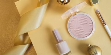 Cosmetic products set with festive decor on golden platform. Top view, flat lay