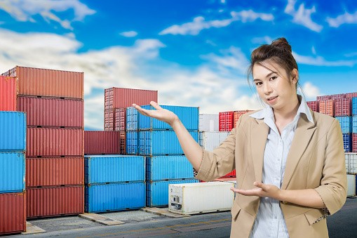 asian young business woman on industrial port with container yard background.