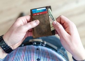 A picture of a person who used a Red Shield Administration vehicle protection plan putting saved money in their pocket.