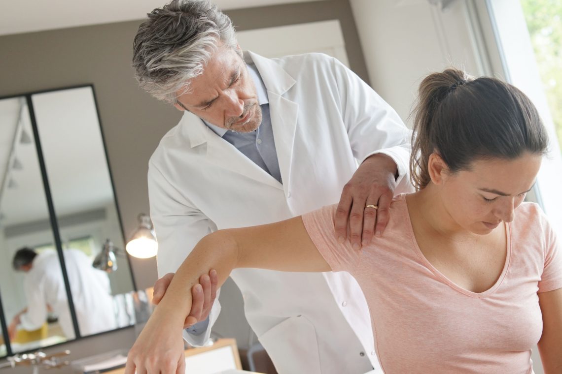 Physiotherapist helping patient with shoulder injury