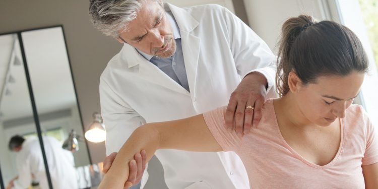 Physiotherapist helping patient with shoulder injury
