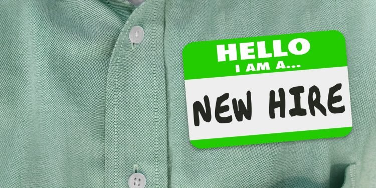 New Hire nametag on a green shirt worn by a new employee or fresh talent just brought onboard to a company or business