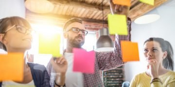 Business people meeting at office and use post it notes to share idea. Brainstorming concept. Sticky note on glass wall.