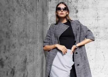 high fashion portrait of young elegant woman outdoor. Grey сoat, cat eye sunglasses, grey wall background