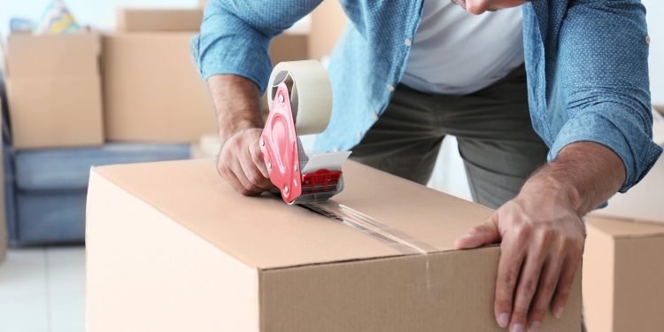 House moving concept. Closeup of man packing cardboard box