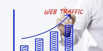 Businessman hand writing Web Traffic graph  with red marker on transparent wipe board, business concept.