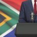 Businessman or politician making speech from behind the pulpit with national flag on background - South Africa
